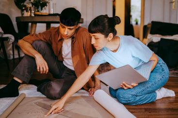 Young female freelancer pointing at blueprint while...
