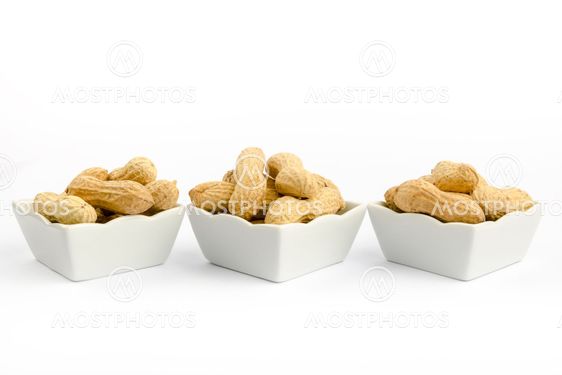 Three white bowls filled with peanuts on a white background
