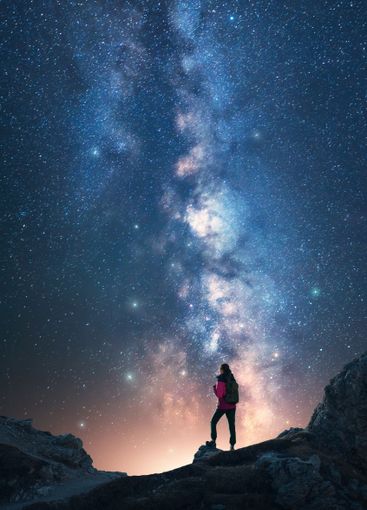 Milky Way and woman on mountain peak at starry night....
