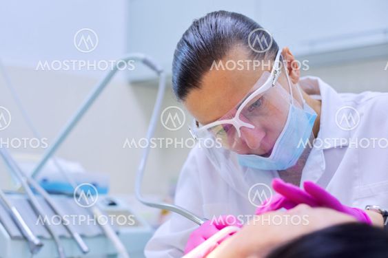 Experienced dentist treats teeth in patient, care and...