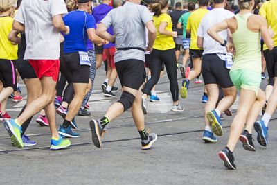 Marathon runners running race people feet on city road 