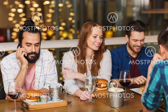 man with smartphone and friends at restaurant