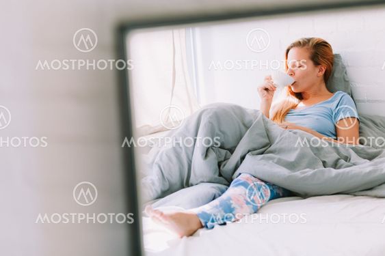 Young woman drinking coffee in bed