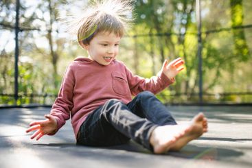 Little boy jumping on a trampoline in a backyard on warm...