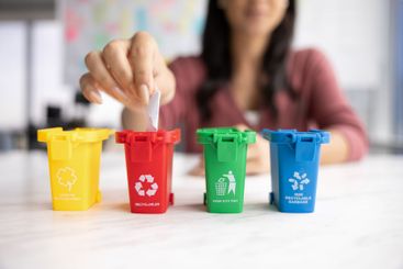 Latin woman sorting trash into four colorful tiny toy bins