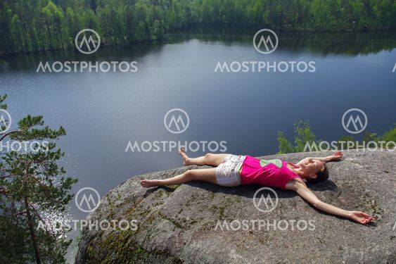 woman laying on cliff an relaxing above the lake Yastrebinoye, Priozersky district in Leningrad region, Russia