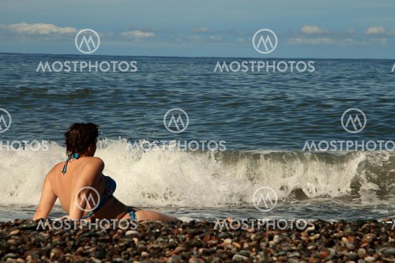 Woman sitting on shore of the sea on the beach