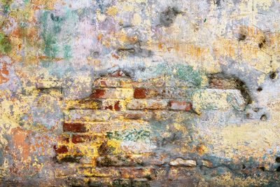 Old damaged multicoloured brick wall.