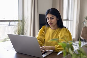 Young Indian woman lead digital communication using laptop