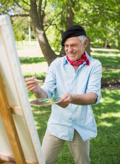 Happy mature man painting in park