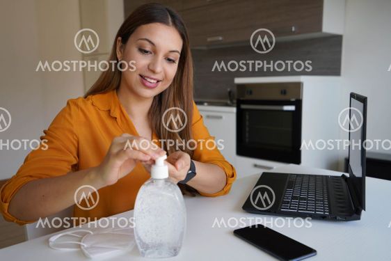 Home working. Beautiful woman using hand alcohol gel or...