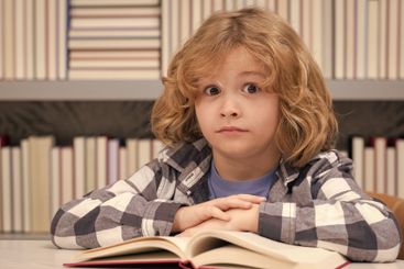 Childhood and education concept. Kid reading a book in a...