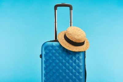 blue colorful travel bag with handle and straw hat...