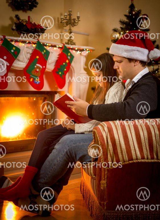 father sitting with daughter at fireplace and telling story