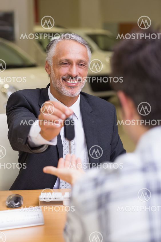 Smiling salesman giving a customer car keys