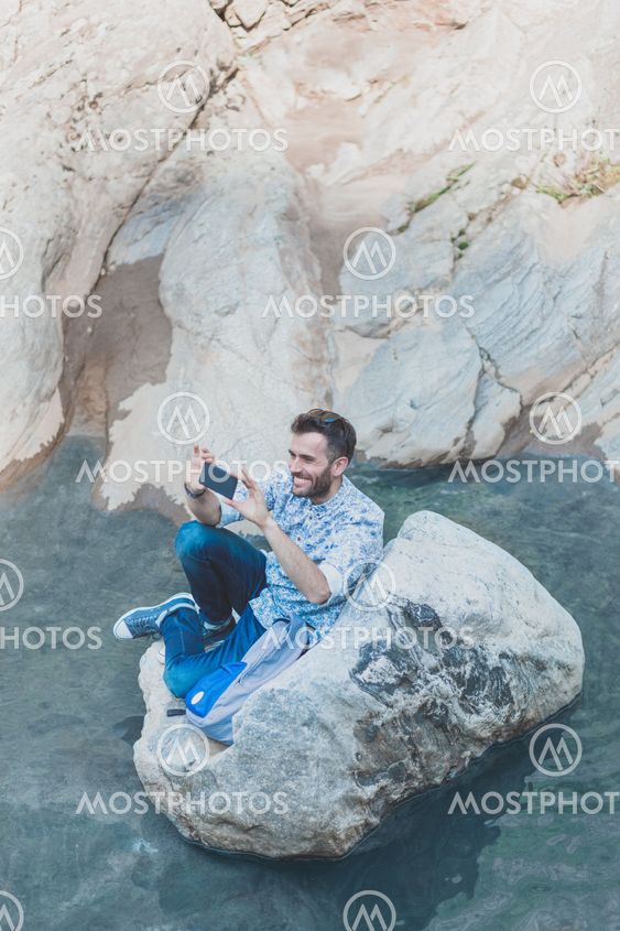 Beautiful young man using smartphone in the nature