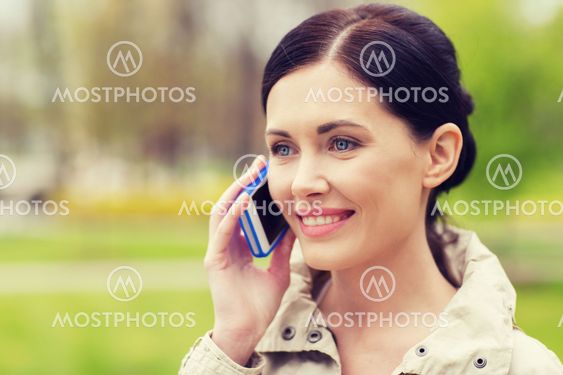 smiling woman calling on smartphone in park