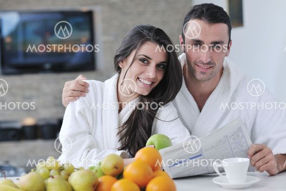 Happy couple reading the newspaper in the kitchen at breakfast