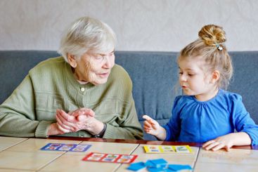 Beautiful toddler girl and grand grandmother playing...