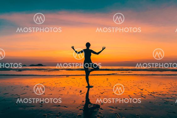 Silhouette young yoga woman on the beach at amazing sunset.