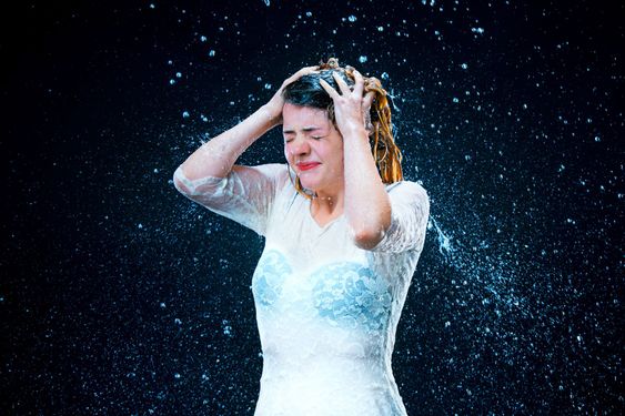 The young girl standing under running water