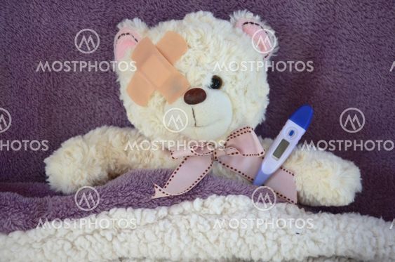 Ours en peluche sous une couverture avec de la fièvre
