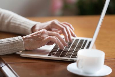 Female hands typing on keyboard, senior woman working on...