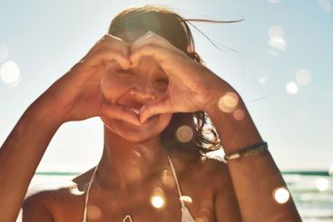 Woman, portrait and heart hands at ocean for travel,...