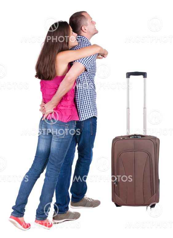 Back view of young couple traveling with suitcas .