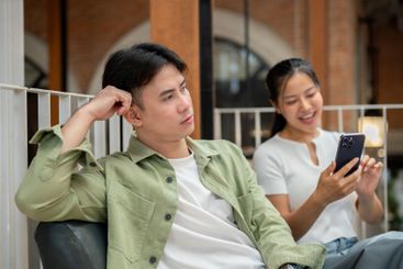A man is sitting on a couch in a cafe with a moody...