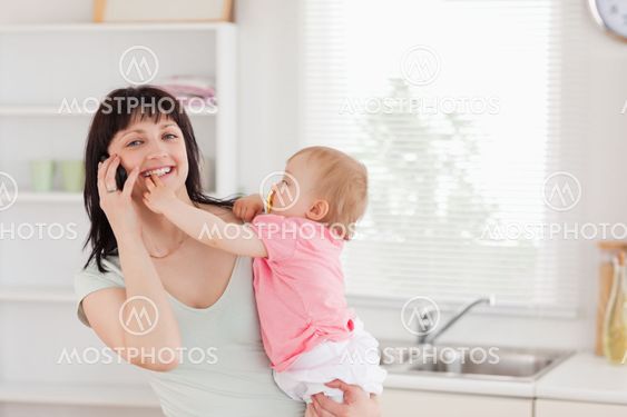 Lovely woman on the phone while holding her baby in her arms
