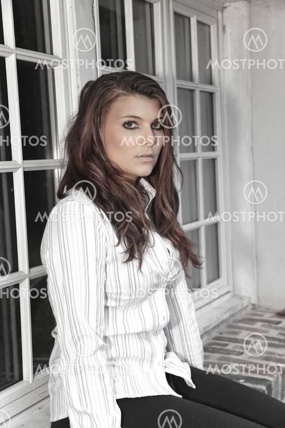 portrait of a young woman sitting on the windows in white shirt