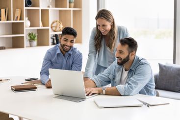 Three multiracial colleagues working together using laptop