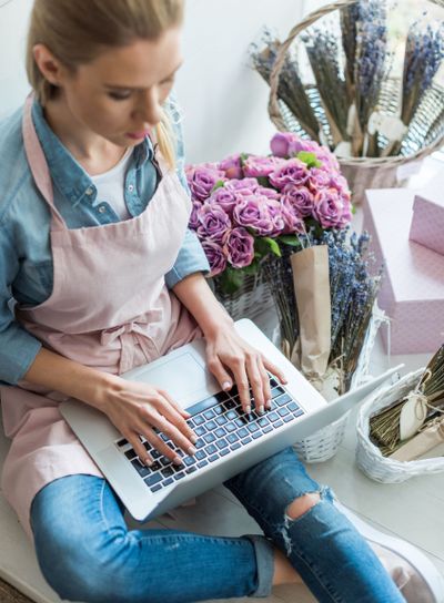 high angle view of young woman in apron using laptop in...