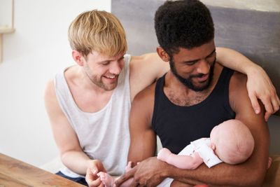 Loving Male Same Sex Couple Cuddling Baby Daughter At...