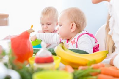 Cute baby girl eating healthy solid food in a modern...