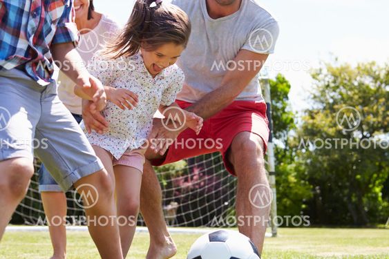 Family Playing Football In Garden Together
