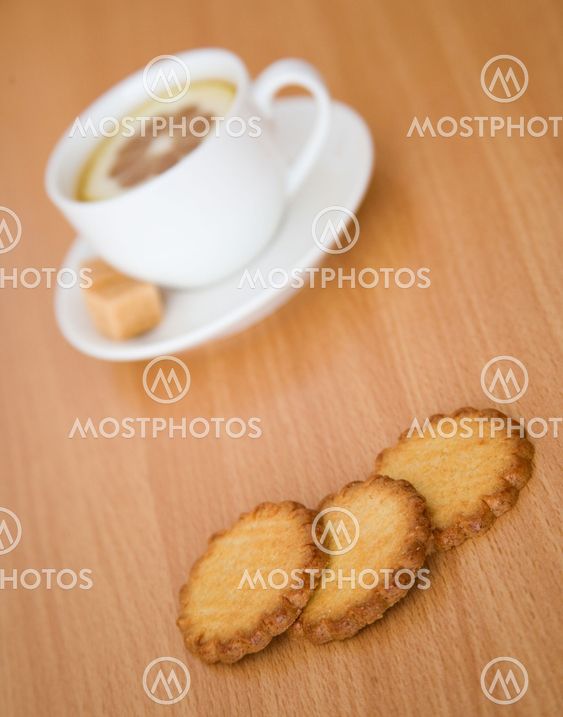 Cup of black tea with lemon, sugar and biscuits. Focus on biscuits