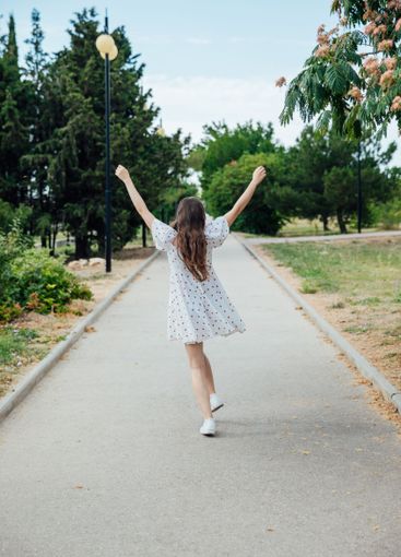 brunette woman in white polka dot summer dress walking...