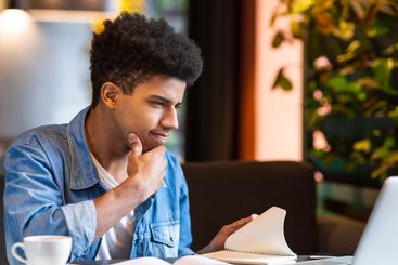 Concentrated Young Guy Using Laptop at Table