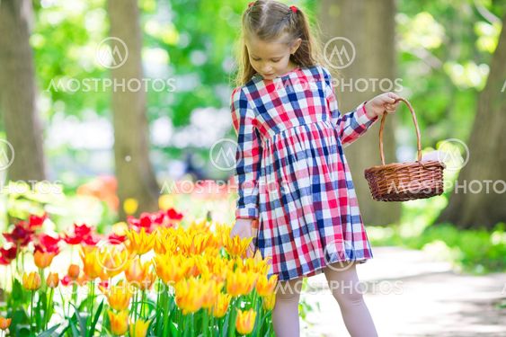 Little adorable girl with flowers in tulips garden