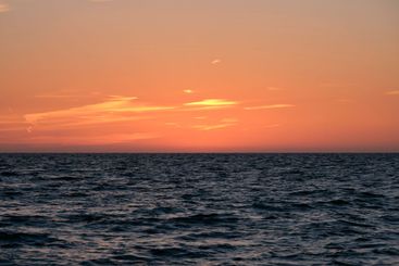 Dramatic bright red sky at ocean sunset, soft evening...