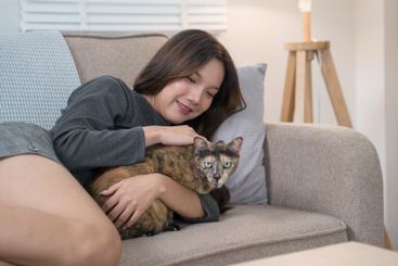 A woman lying on a couch, lovingly cuddling with her...