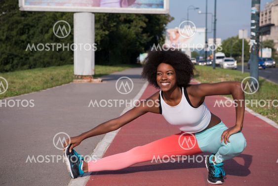 Portrait of sporty young african american woman stretching outdo