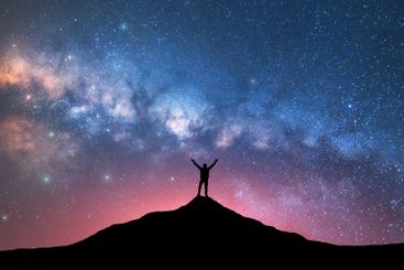 Milky Way and happy man with raised up arms on the...
