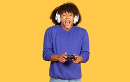 Young black man enjoys gaming with headphones on a...