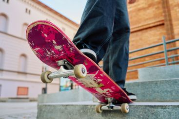 Close-up of skateboarder on pink skateboard at street