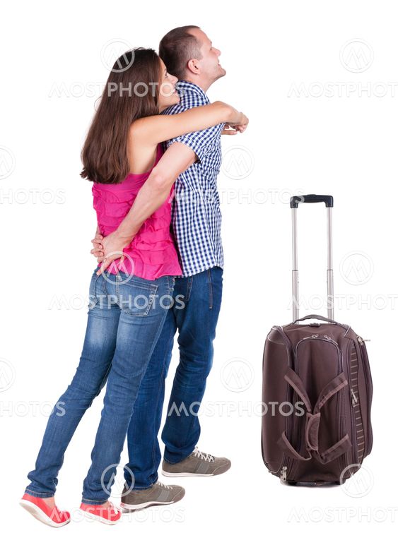 Back view of young couple traveling with suitcas .