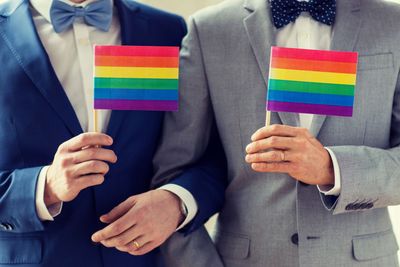 close up of male gay couple holding rainbow flags