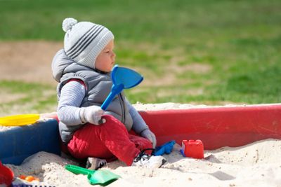 One year old baby boy toddler at playground sandbox